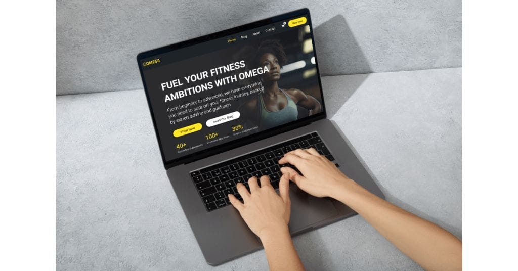 Hands typing on a laptop with a website open, promoting a fitness program called "Omega." The site features text about fueling fitness ambitions, benefits like increased energy and muscle growth, and options for a 30% discount. The background is a gray surface.